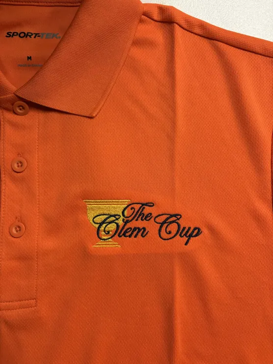 The Clem Cup golf logo embroidered on an orange polo